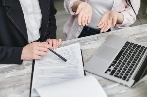 insurance agent pointing at a document with a pen, explaining details to a client