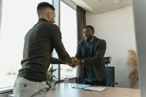 insurance agent shaking hands with a client at his desk